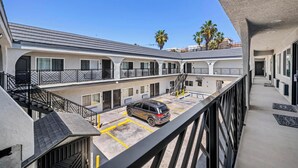 A multi-story hotel with a parking area, balconies, and a staircase.