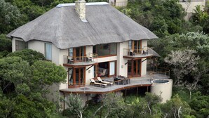 A house with a thatched roof, multiple balconies, and a pool.