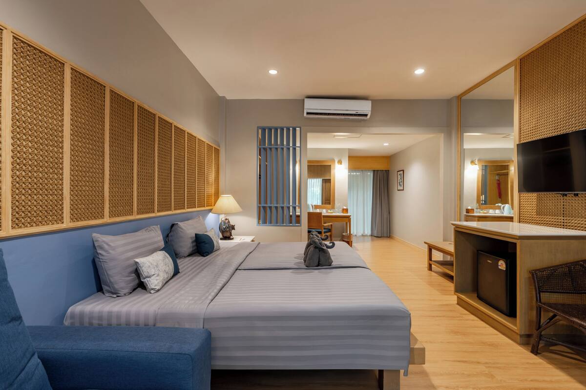 A hotel room with a bed, a desk, a TV, and a seating area.