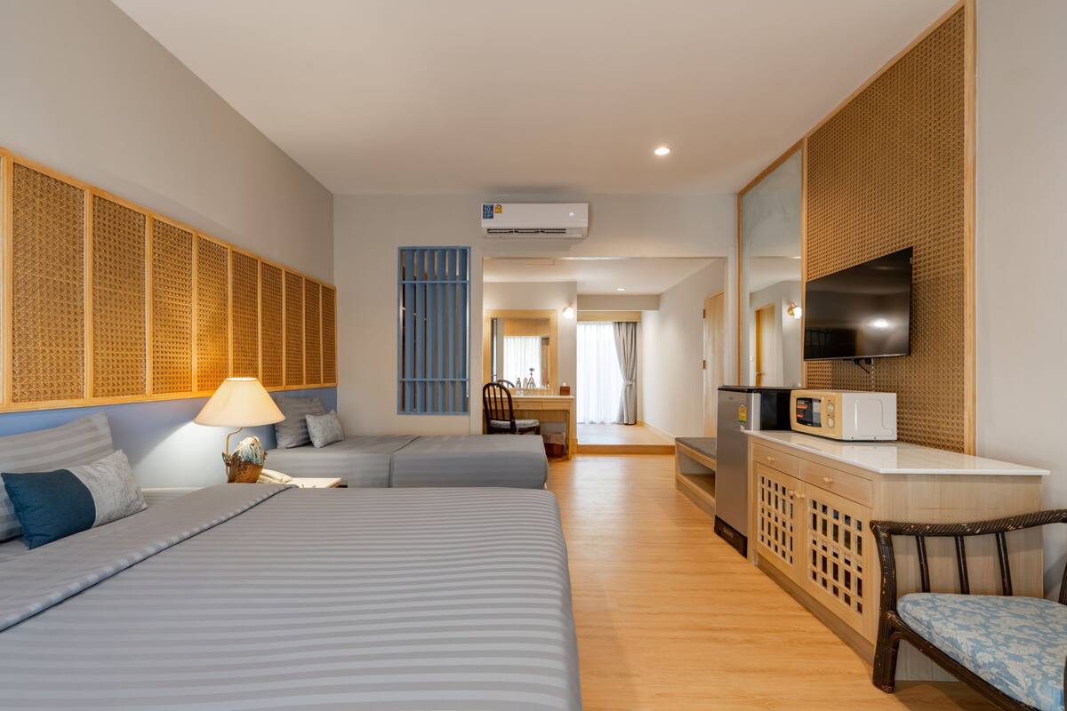 A hotel room with a large bed, a desk, a TV, and a kitchenette.