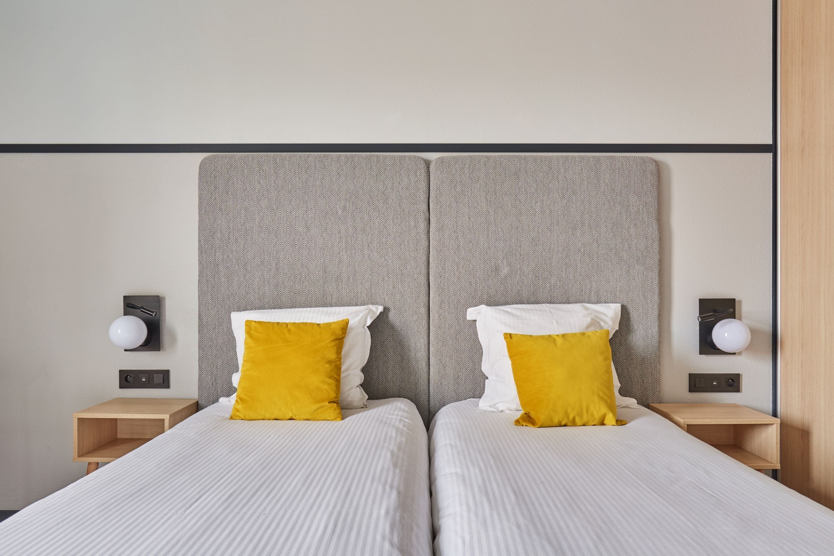 A double bed with two pillows, a bedside table, and a wall-mounted lamp.