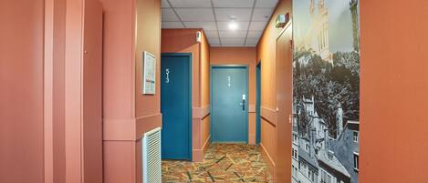 Un couloir aux murs orange, avec un tapis à motifs et des portes numérotées 513 et 514.
