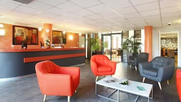 Et moderne receptionområde med disk, røde og grå lænestole og et glasbord.