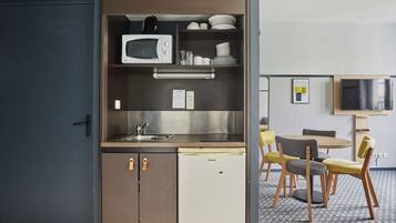 A compact kitchenette with a microwave, sink, and small refrigerator. There is a dining area with a table and chairs.