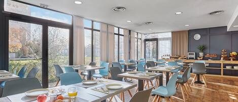 A modern dining area with tables, chairs, and breakfast items.