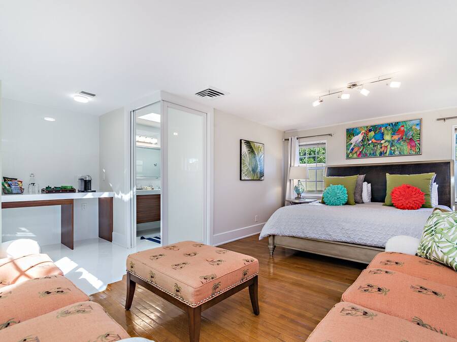 A modern bedroom with a bed, a desk, and a seating area.
