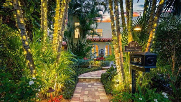 A well-lit pathway leading to a house with a sign reading "1608 Grandview Gardens".