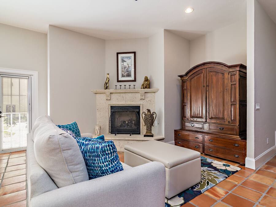 A living room with a fireplace, a sofa, a cabinet, and a door.