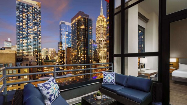 Ein Balkon mit Blick auf die Stadt, ausgestattet mit einer Couch, einem Couchtisch und Zierkissen.