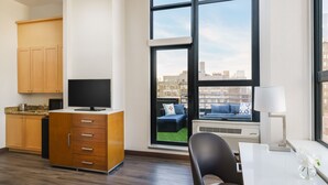 Ein modernes Wohnzimmer mit großem Fenster, Flachbildfernseher, Esstisch und Sofa.