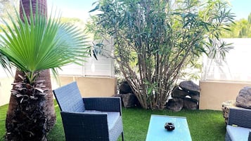 Une terrasse dotée de meubles en osier, d’un palmier et d’une plante de bambou.