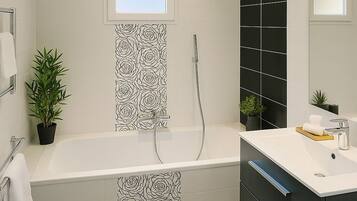 Een moderne badkamer met een badkuip, een douche, een wastafel met spiegel en een potplant.