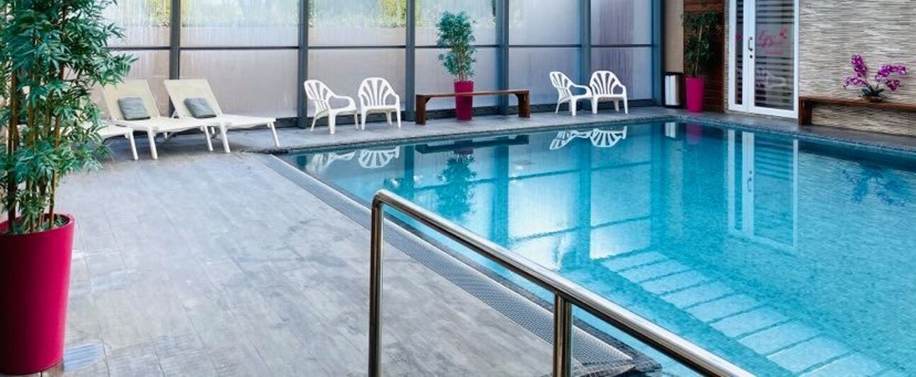Una piscina con sillas de descanso y plantas en macetas.