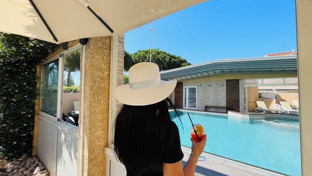 A person standing by a pool with a view of a building and a clear sky. - Hotel & Spa GIL DE FRANCE Cap D'Agde (Agde)