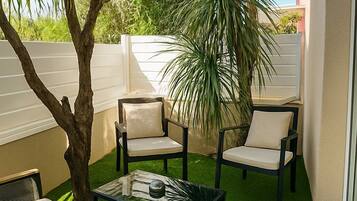 An outdoor patio with a sofa, two chairs, a coffee table, and a small tree.