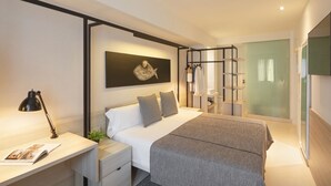 A modern bedroom with a bed, bedside table, lamp, and a wall-mounted shelf. - Hotel Denit Barcelona (Barcelona)