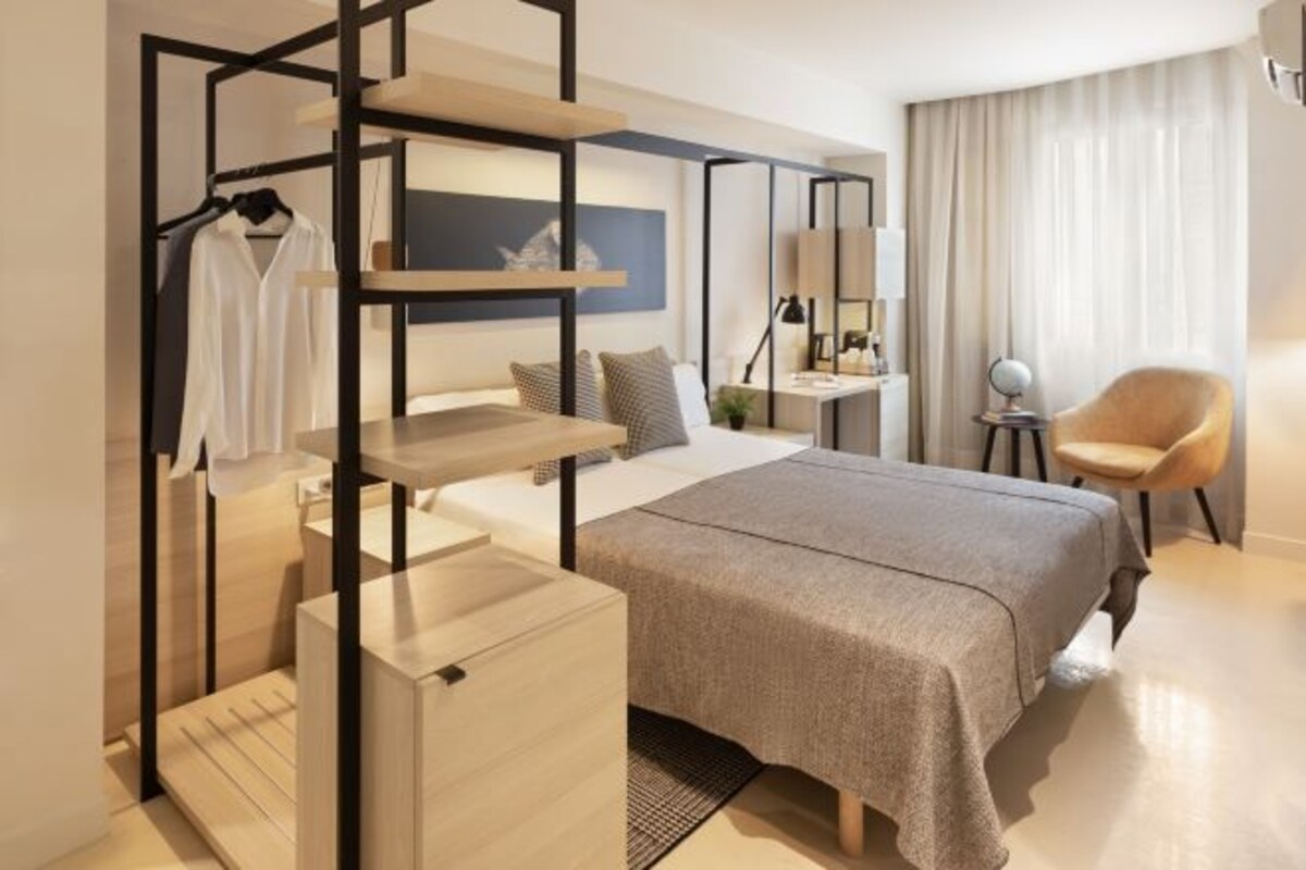 Una habitación de hotel moderna con cama, zona de estar, escritorio y silla.