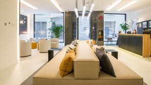 A modern reception area with a sofa, chairs, and a reception desk. - Hotel Denit Barcelona (Barcelona)