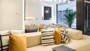 A modern living room with a sofa set, decorative pillows, a coffee table, and a large window with a view. - Hotel Denit Barcelona (Barcelona)