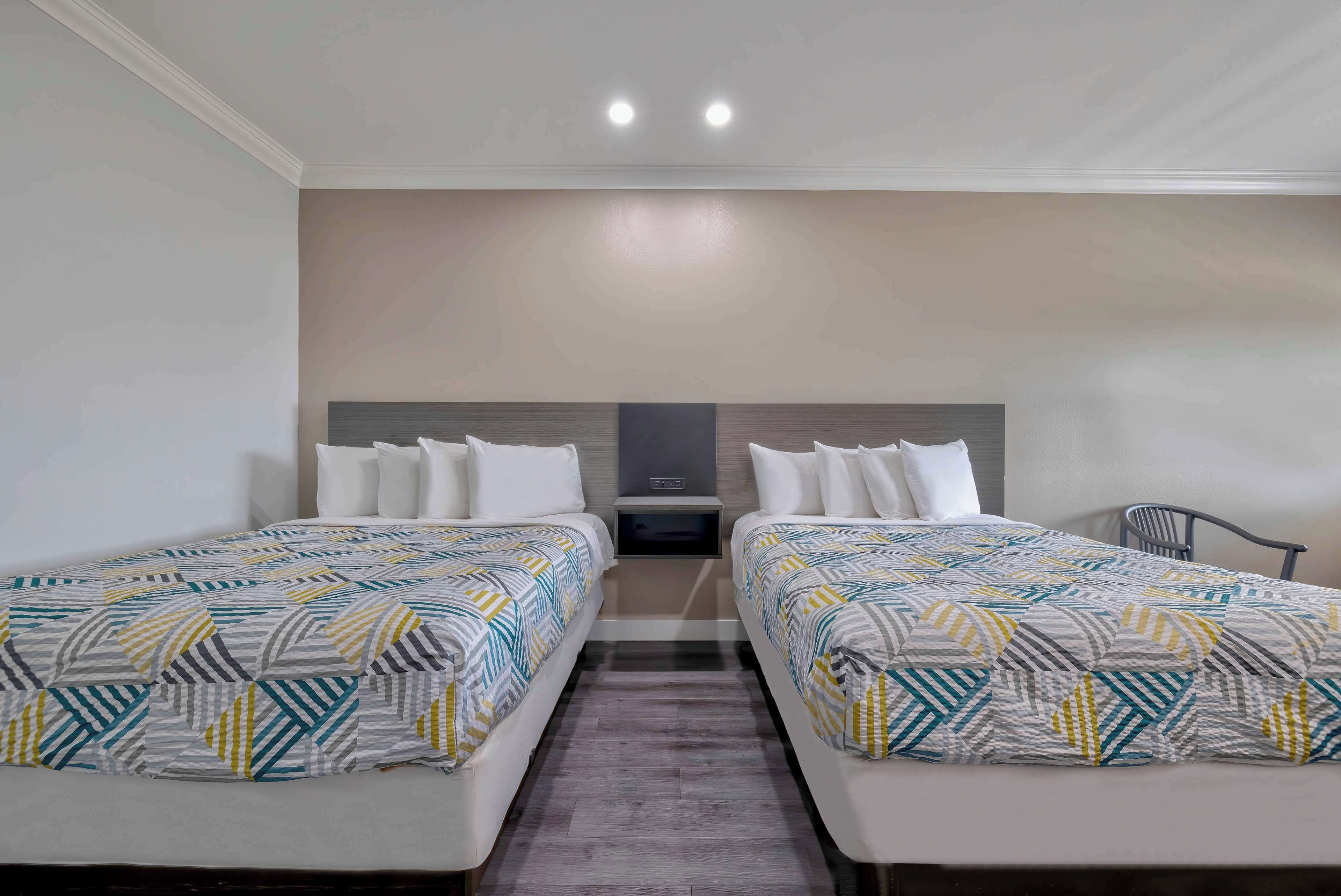 A hotel room with two beds, a TV, and a chair.