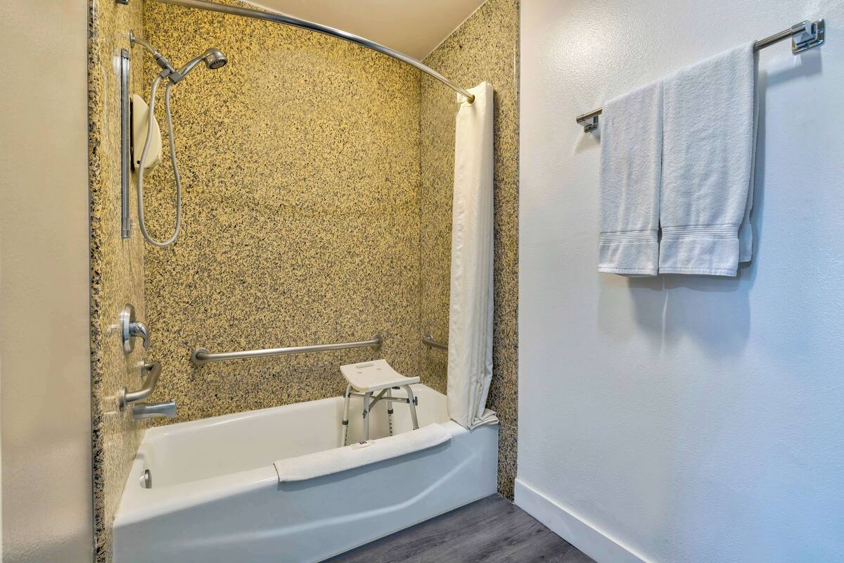 A bathroom with a bathtub, shower, and a towel rack.