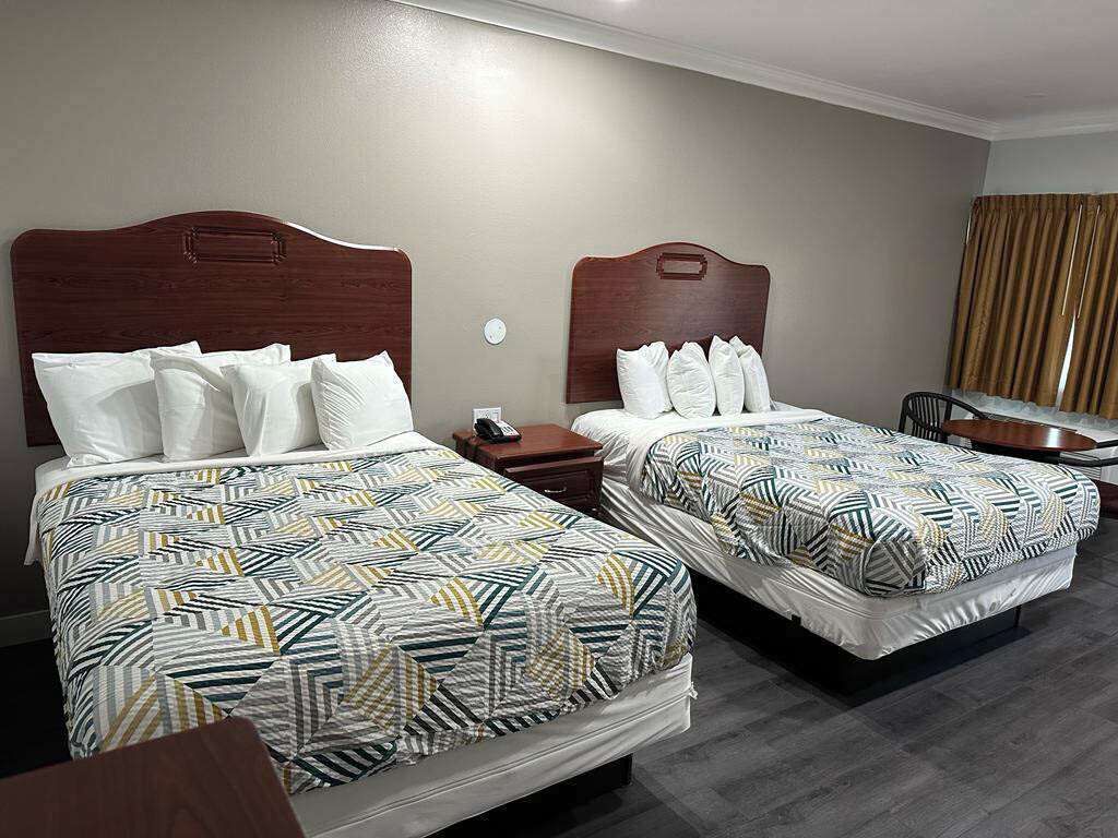 A hotel room with two beds, each with patterned bedding and wooden headboards.
