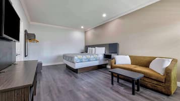 Een hotelkamer met een bed, een bank, een televisie en een bureau.