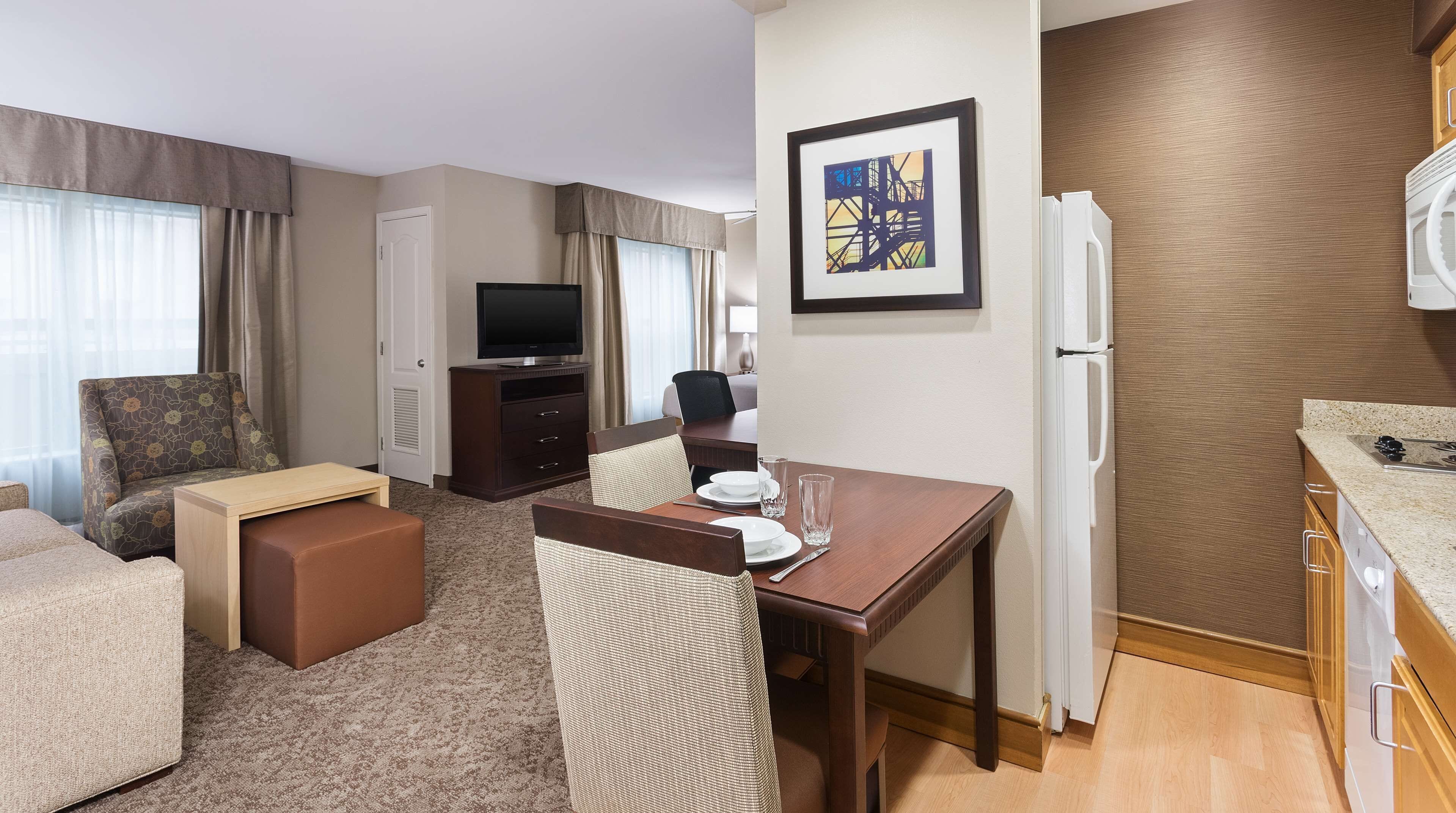 Une chambre d’hôtel équipée d’un coin repas, d’une télévision, d’un réfrigérateur et d’un plan de travail.