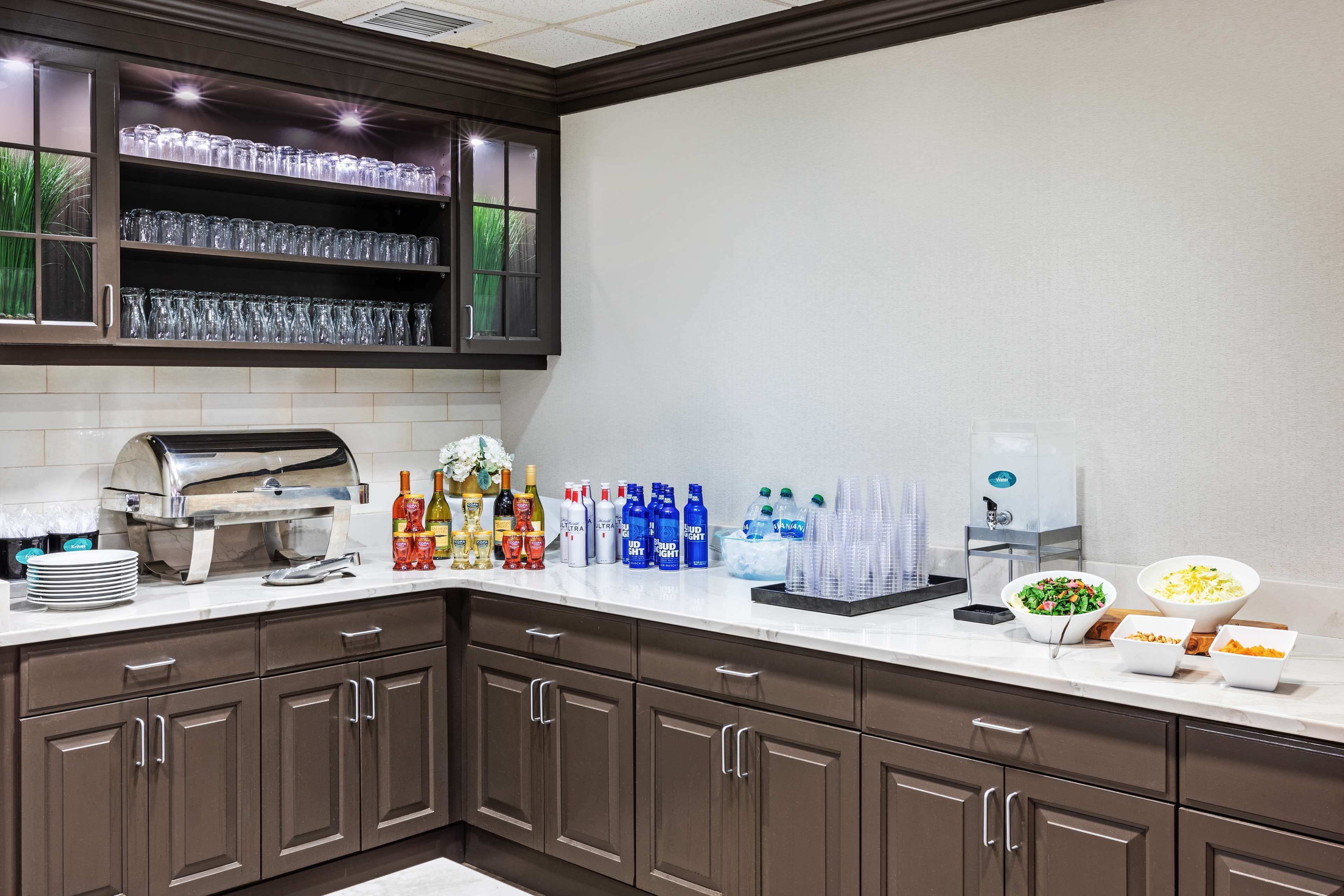 A kitchen with a built-in grill, a beverage station with various drinks, and a salad bar.