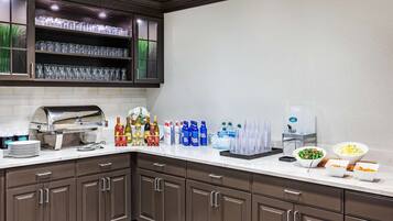A kitchen with a built-in grill, a beverage station with various drinks, and a salad bar.