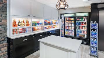 Un área de cocina bien iluminada con una isla blanca, armarios negros y una variedad de alimentos y bebidas en el refrigerador y el congelador.