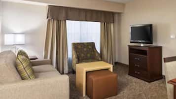 A hotel room with a sofa, a small table, a television, and a cabinet.