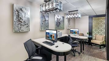 Um espaço de escritório moderno com duas mesas, cadeiras e arte decorativa na parede de metal.