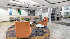 A spacious lobby with a high ceiling, modern furniture, and a central staircase.