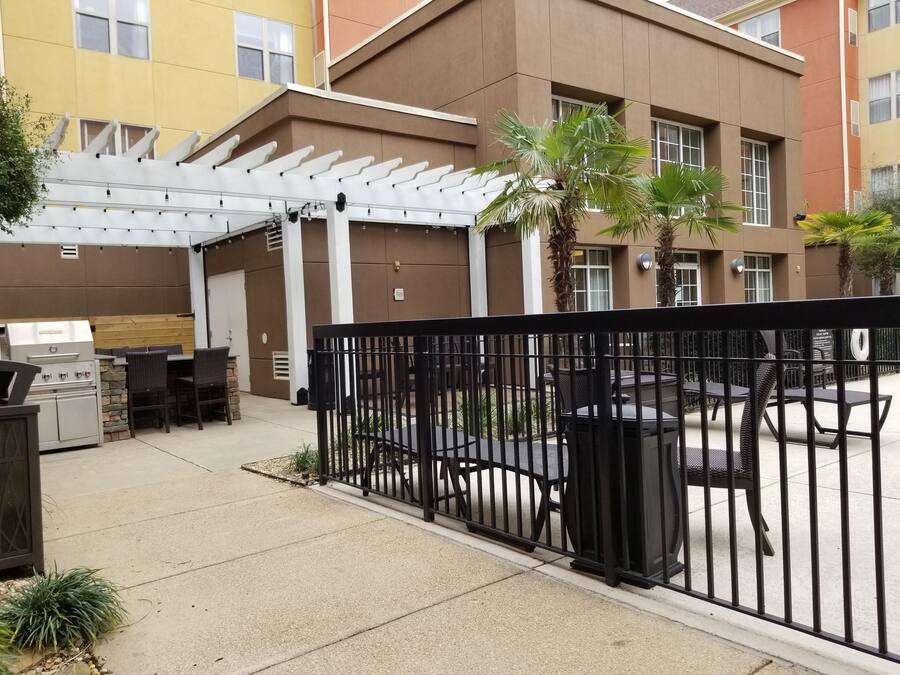 Área de pátio externa com churrasqueira, assentos e pérgola.