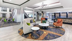 A spacious lobby with a central seating area, a staircase, and a reception desk.