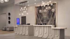 A hotel reception area with marble wall and a large screen displaying the Hilton logo. - Hilton Phoenix Chandler (Chandler)