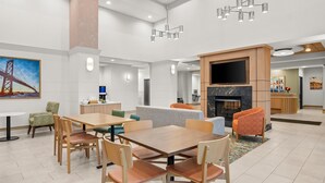 A spacious indoor area with a large wooden table and chairs, a fireplace, and a television. - Hampton Inn & Suites Detroit-Canton (Canton)