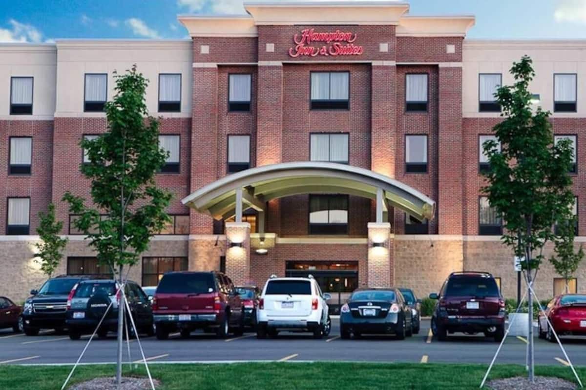 A brick building with a marquee sign reading 'Hampton Inn & Suites.'