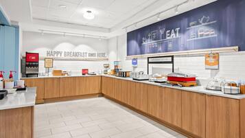 A modern breakfast area with a counter, coffee machine, and various breakfast items.