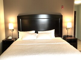 Habitación de hotel con una cama grande, dos mesitas de noche y dos lámparas de pared.
