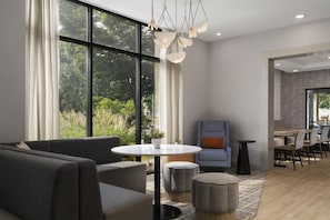 Un intérieur moderne avec un canapé, une table ronde et des chaises, de grandes fenêtres avec des rideaux et un coin repas.