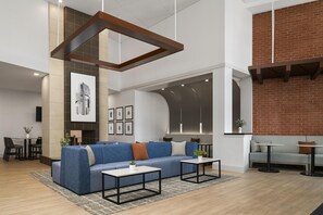 Een modern interieur met een blauwe zithoek, een salontafel en een bakstenen muur.