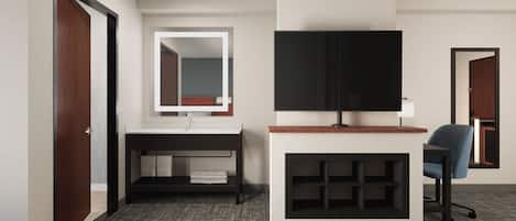Habitación de hotel con puerta de madera, baño con espejo, televisión de pantalla plana, escritorio y una silla.
