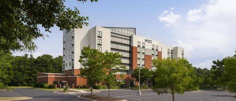 A modern hotel with a brick facade, multiple floors, and a parking lot with marked spaces.