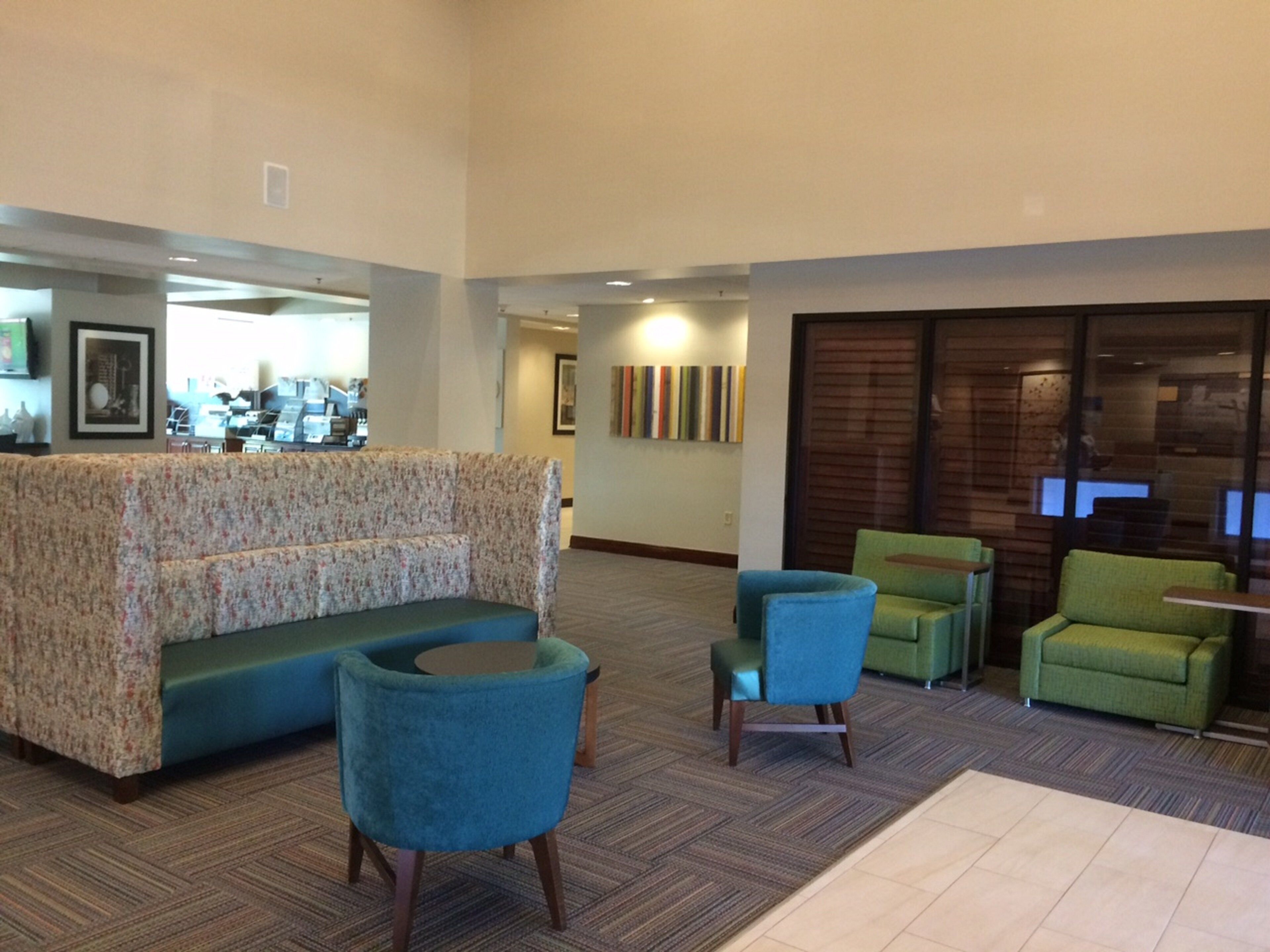 A lobby with a sofa, two armchairs, and a coffee table. There is a reception desk in the background.