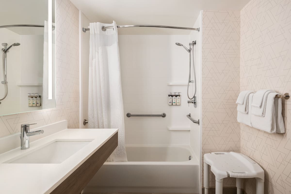 Un baño moderno con bañera, ducha y tocador con espejo.