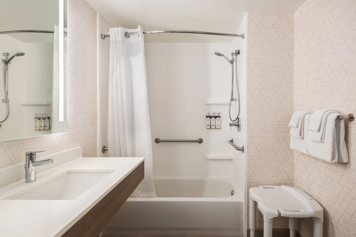 Une salle de bain moderne équipée d’une baignoire, d’une douche et d’un meuble-lavabo avec un miroir.