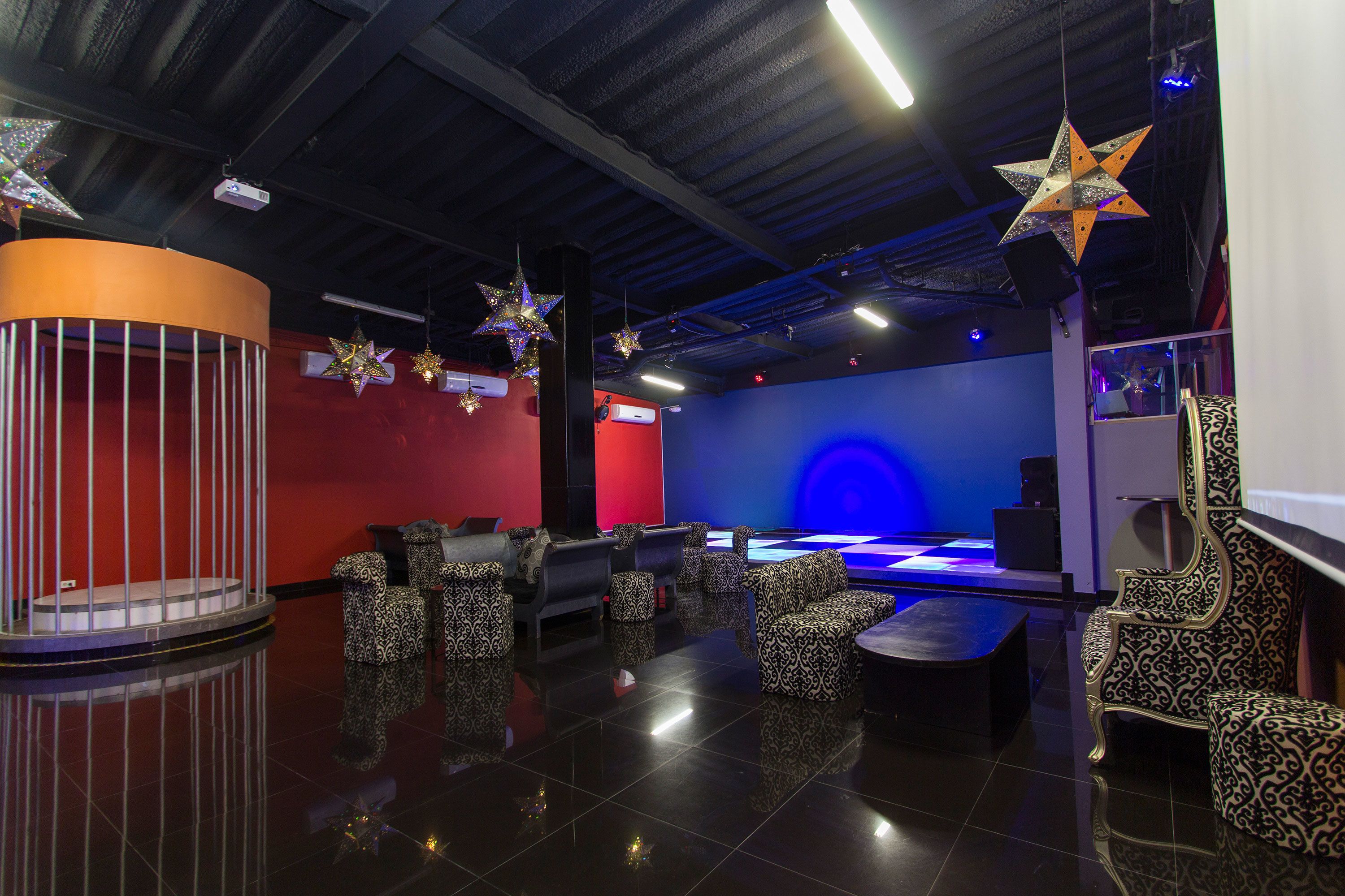 A modern lounge area with patterned seating, a stage, and star decorations.
