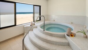 A spa area with a hot tub, steps leading to it, and a view of the beach. - Grand Decameron Los Cabos, A Trademark  Resort (San José del Cabo)